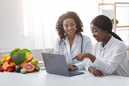 非洲妇女人口统计家和病人在饮食学家内阁看笔记本电脑屏图片