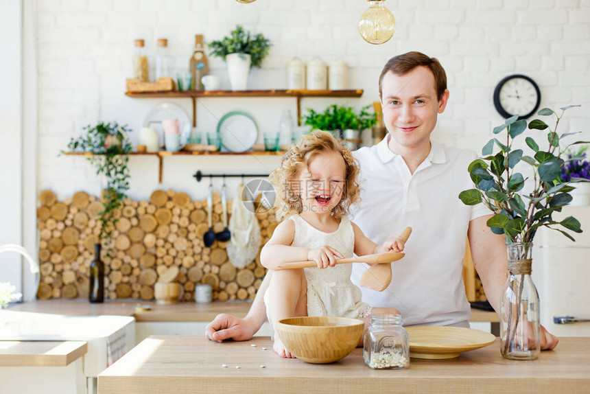一个小女孩正在餐桌旁明亮的斯堪的纳维亚风格的厨房里玩耍父亲和女儿玩沙砾蒙台梭利教育理图片