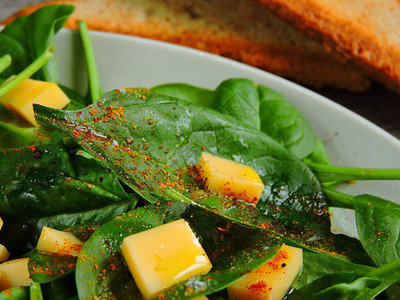 用菠菜吃午餐配菜的美味沙拉和盘子上的菠菜图片