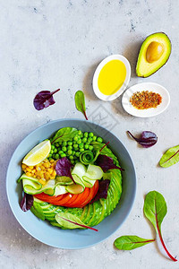 新鲜蔬菜黄瓜番茄玉米青豆鳄梨蓝底的碗里生菜健康饮食概念图片