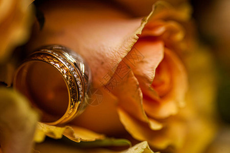在婚礼当天关闭了两个结婚戒指和红玫瑰的婚礼花束图片