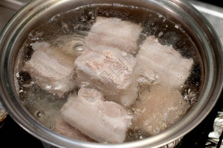 在沸水中煮猪肉在煤气炉灶图片
