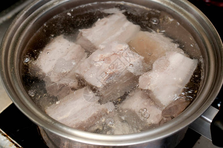 在沸水中煮猪肉在煤气炉灶图片