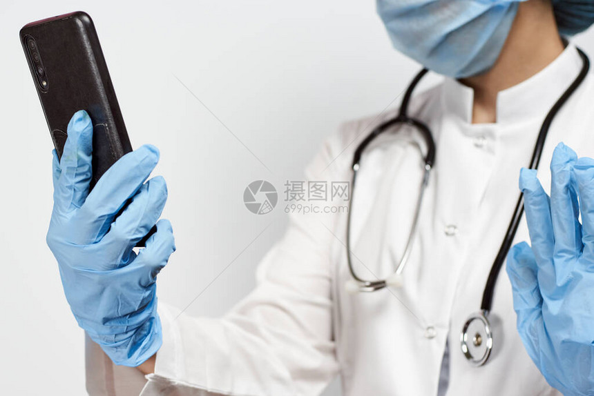 医疗保健系统工作人员手持机持防护医疗装备在休息时间的女医生护士通过缩放视频通图片