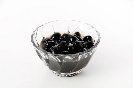 白色背景玻璃碗中煮沸的黑豆图片