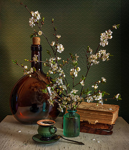 桌上放着一杯香浓的咖啡和一束春天的花束倒映着鲜花和杯子的大瓶子老书图片