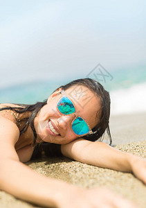 快乐的女士躺在岸上享受阳光和户外的水图片