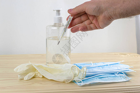 医疗保护卫生面罩橡胶手套和透明瓶装的洗涤剂在桌子上图片