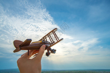 蓝天背景上拿着木制飞机的手图片