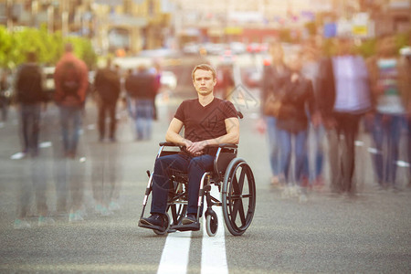 残疾男子坐在路边的轮椅上流着人流图片