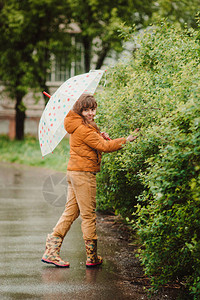 穿着黄色大衣和多彩雨伞的快乐女孩图片