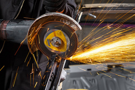 汽车修理工使用金属磨床在汽车修理店的虎钳中切割汽车静音块的特写镜头背景图片