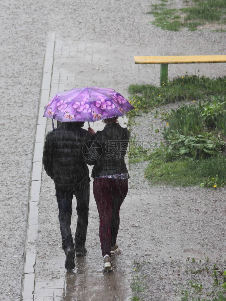 人们在一把粉红色的雨伞下穿着深色衣服图片