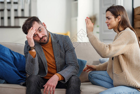 愤怒的妻子在沙发上与丈夫一起坐在家中尖叫和争吵图片