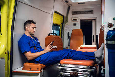 身穿蓝色制服的男护理人员在救护车里休图片