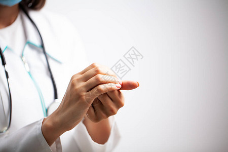 穿白色大衣的女医生用抗消毒剂给自己图片