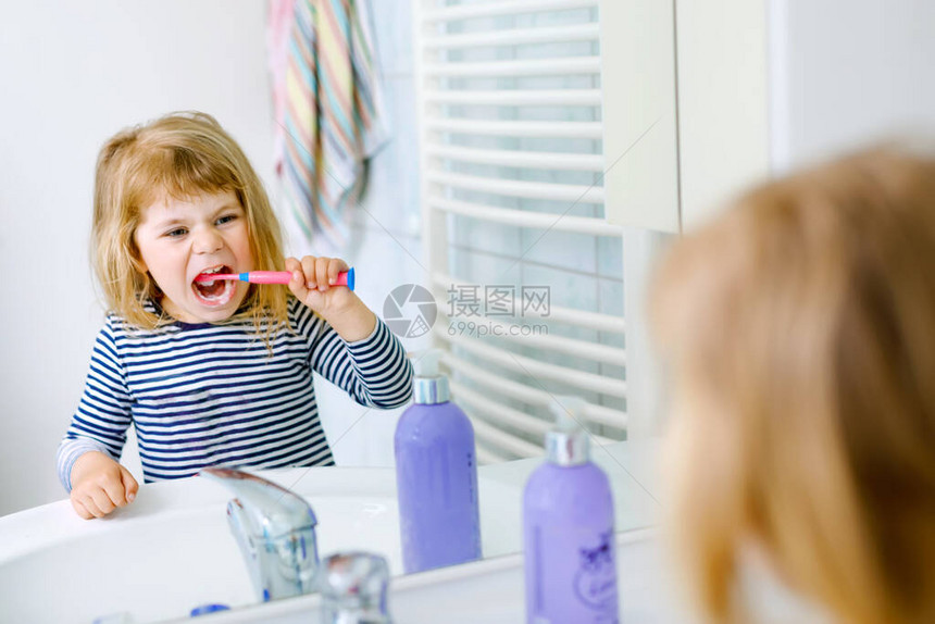 手里拿着牙刷的可爱小女孩清洁牙齿并微笑有趣的快乐健康孩子早上洗脸和清图片