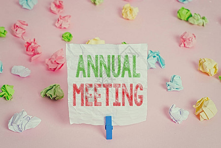 显示年会的文本符号商业照片展示了一个组织感兴趣的股东的年度聚会彩色皱巴的纸空提醒粉红色背景图片