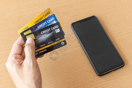 拿着信用卡和智能手机的人使用智能手机在互联图片