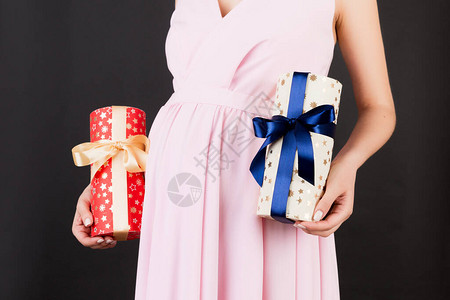 穿着粉红色裙子的孕妇紧贴身着两盒黑底礼物图片