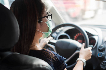 戴防护面罩和手控方向盘的年轻女在车内对抗冠状或冠状图片