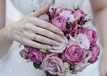 有戒指的新娘的手拿着婚礼花束婚礼装饰品特写图片