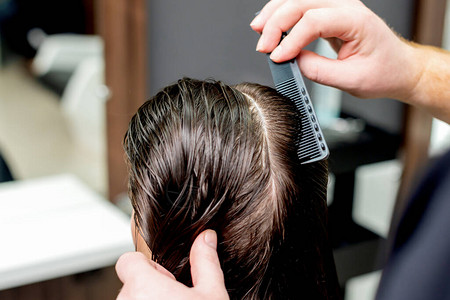 在美发沙龙理发女人的头发美发师手在美发沙龙梳理女图片
