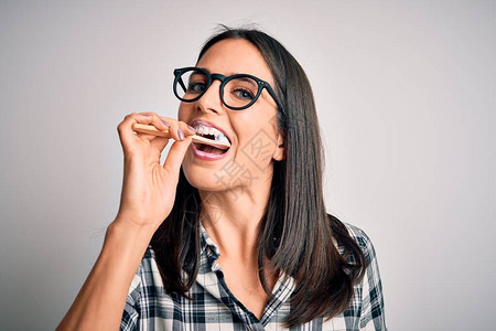 戴眼镜的年轻白人女用牙刷和口腔膏刷牙清洁牙齿和舌头作为健康的图片