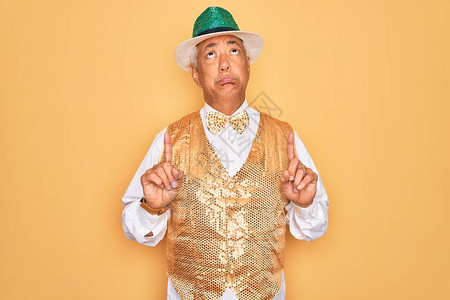 中年灰色头发的老人穿着黄色背景的巴西狂欢节服装图片