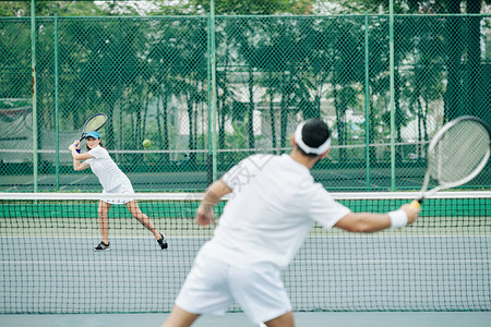 微笑的年轻女子在户外与男朋友打网球图片