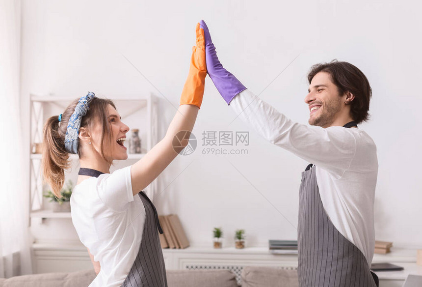 快乐的年轻配偶们在一起打扫平板之后相互给予高五人图片