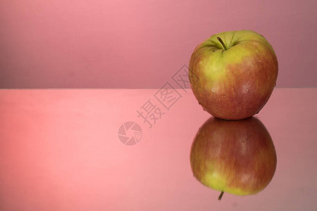 红苹果在镜子红色背景上的镜像桌子上图片
