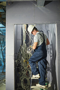 高级电工在翻修房屋时用电线柜子连接电缆的全长图片