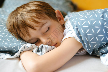 可爱的男孩睡在他的床上累了可爱的孩子在卧室里早上起床的时间图片