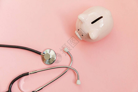 医学生设备听诊器和储钱罐隔离在粉红色柔和的背景医疗保健财务检查或节省医疗保险费用概念平躺顶背景图片