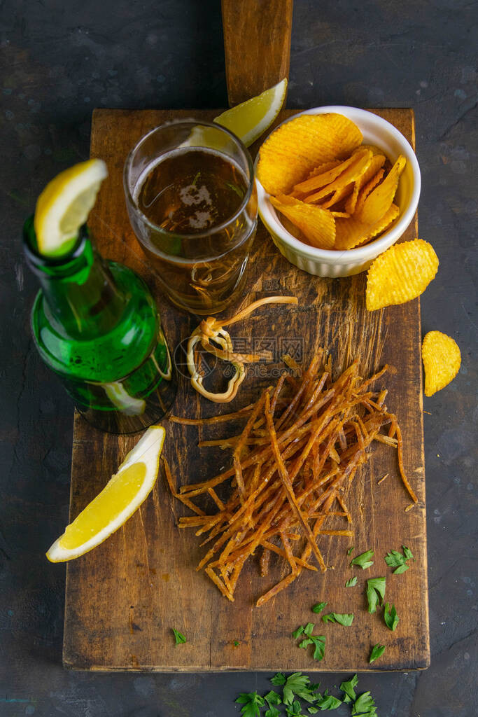 黑木板上涂满胡椒和啤酒柠檬和薯片的鲑鱼蜘蛛网图片