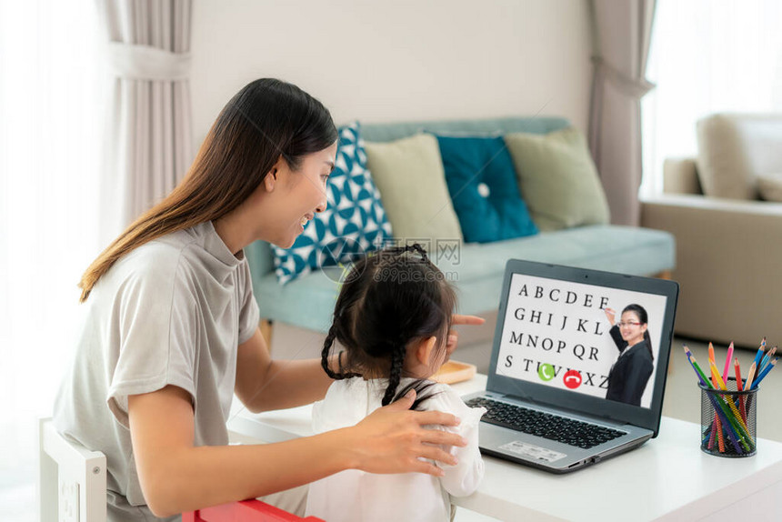 亚洲幼儿园女学生与母亲视频会议在家里的与老师在笔记本电脑上进行电子在家上学和远程在线图片
