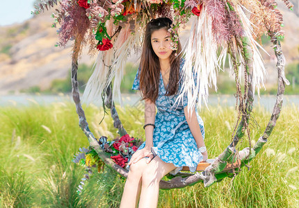 快乐的美丽的亚洲女在自然田中的花朵摆动上放松时间享受自然短图片