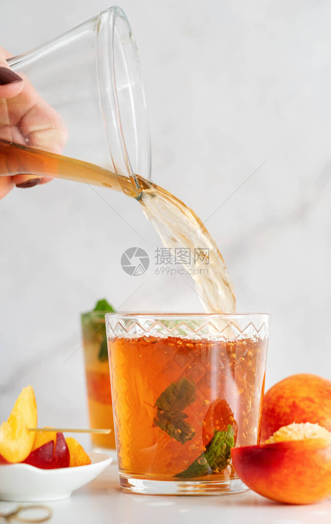 果汁加冰的冷桃子茶水果片和薄荷糖图片
