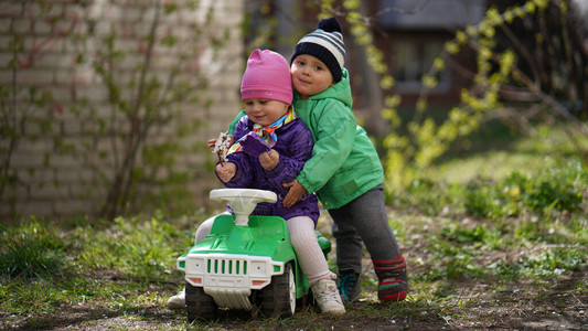 小可爱男孩和女孩在公园早春的一辆绿色玩具车上摆姿势可爱的男孩图片