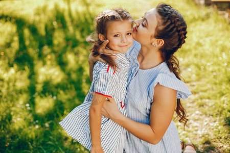 一个漂亮的长发美女妈穿着蓝色礼服站在太阳能公园里和她女儿图片