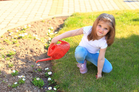 小女孩从花坛上的红色喷壶浇花孩子在园艺帮助照顾图片