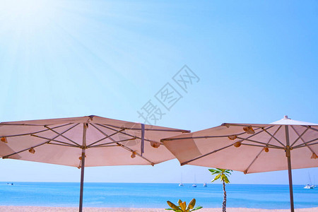 白沙滩和蓝海天空上两把雨伞在阳光明图片