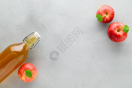 灰石背景的瓶子和红苹果中自制发酵的甘巴沙图片