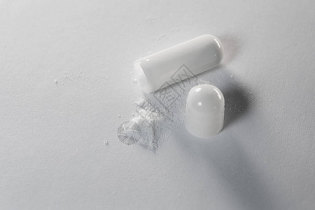 白色底白胶囊配有药粉的白色背景图片