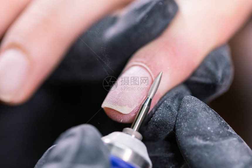 女在美容院使用电动指甲文件钻孔精图片
