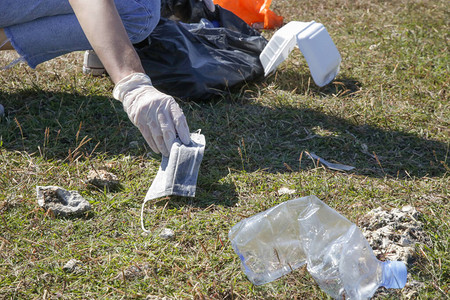 女人从草地上捡起用过的医用口罩环保活动家收集废弃冠状病图片