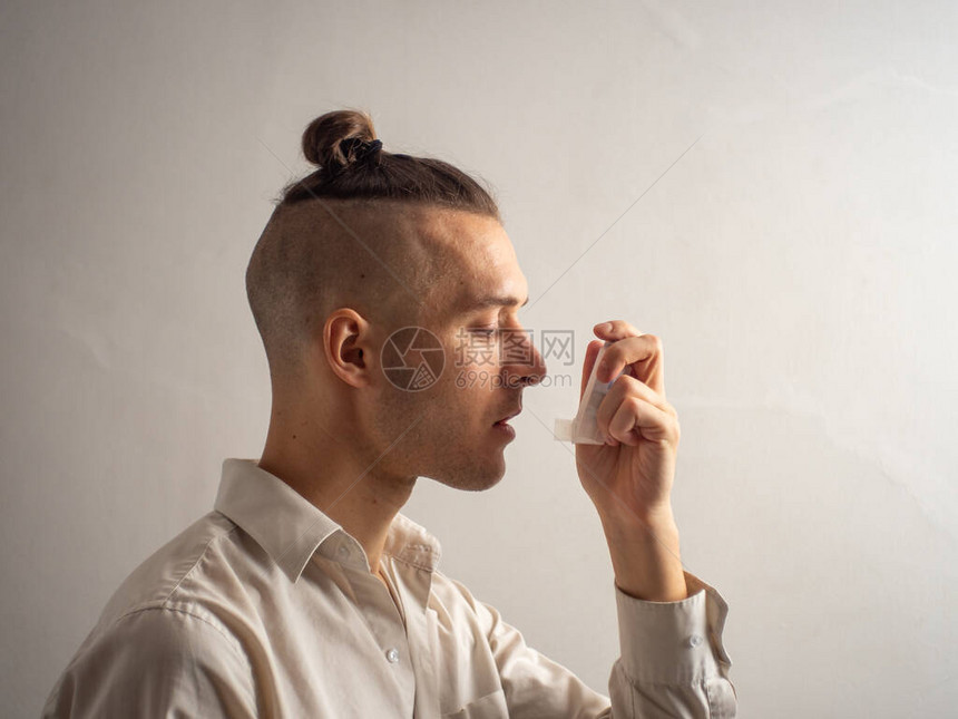 白衫衬衫中的白人男使用沙丁胺醇吸入器处理气喘和过敏图片