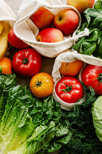 厨房桌子上的生态棉可重复使用袋中的新鲜蔬菜和水果零浪费购物概念图片