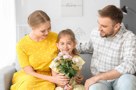 拿着鲜花的小女孩和她的父母在家图片